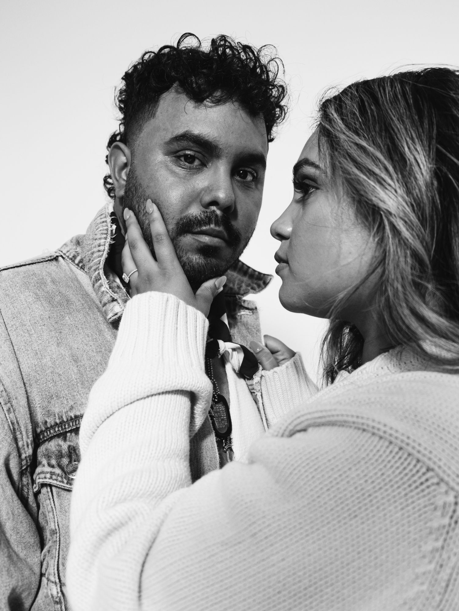 Black and white portrait of the engaged couple, her hand on his face